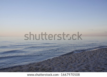 Calm sea on the beach in the very soft colors of the rising sun.