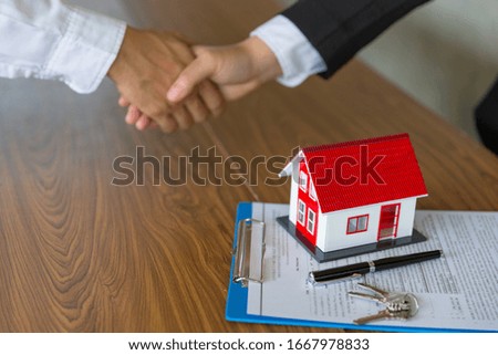 Businessmen and investors in house trading.Holding hands to trust. Hand in hand to make a home purchase contract.Hand in hand with real estate brokers or agents.Is satisfactory Of the contract.