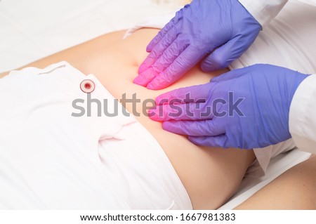 A gynecologist doctor probes the lower abdomen of a girl who has pain and inflammation of the reproductive system. Ovarian cyst, endometriosis, pregnancy pathology Royalty-Free Stock Photo #1667981383