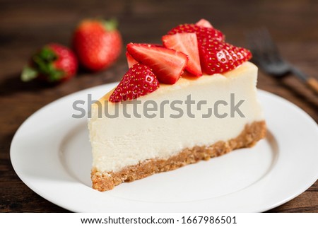 Cheesecake with strawberries on plate, wooden table background Royalty-Free Stock Photo #1667986501