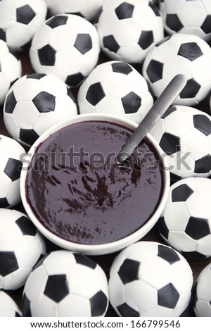 Brazilian culture on the table features a bowl of fresh acai surrounded by football soccer balls
