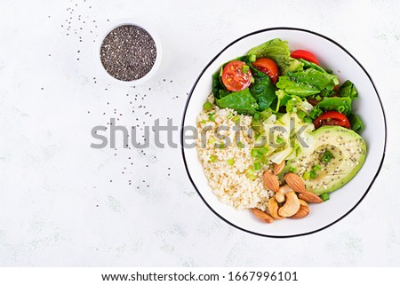 Trendy salad. Vegan Buddha bowl with bulgur, avocado, cucumber, lettuce, tomatoes and chia seeds. International Day Without Meat. Vegetarian salad. Top view, overhead, flat lay