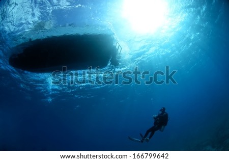 Boat and diver silhouette under wate with beautiful sun ray, Hawaii.