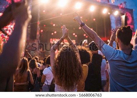 Rear view of group of young friends dancing at summer festival. Royalty-Free Stock Photo #1668006763