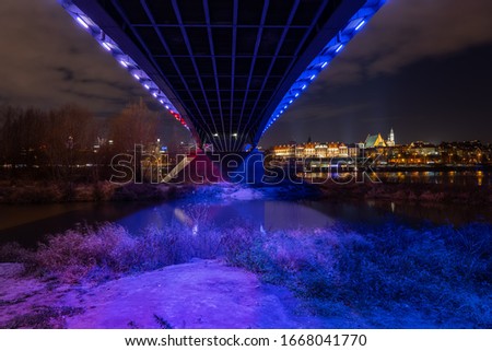 Under the bridge river view of Warsaw city in Poland at night with Old Town skyline 