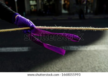 Purple tie tied to an agreement and grabbed by a woman's hand during a feminist protest.