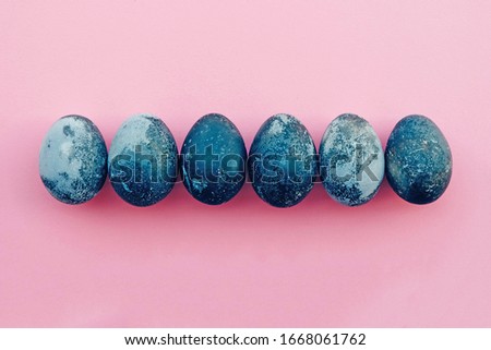 Natural dyed blue colored eggs on pastel pink background, top view. Flat lay. Happy Easter. Copy space.