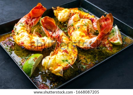 Traditional barbecue spiny lobster tail sliced and offered with saffron lemon sauce as closeup in a metal try  Royalty-Free Stock Photo #1668087205