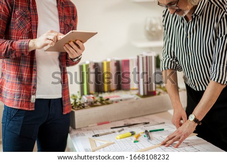young future engineer and professional mature architect engineer co-working in office, they develop new project of building complex constructions with the use of drawings and notes