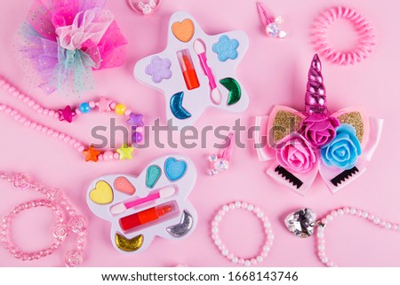 Accessories and cosmetics for a little girl. Lifestyle set on pink