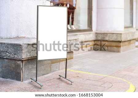 blank street poster stands with space for design near fashion store window in city historical street on spring day