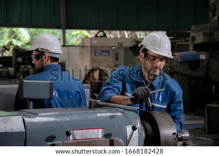 Factory worker working in industrial building indoor. Man fixing machines,Man with White hard hat working in factory