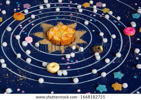 Layout of the solar system of cupcakes, donuts, marmalade, marshmallows, cane sugar. Conceptual photo. Bright sweets. Blue background. Doughnut Day