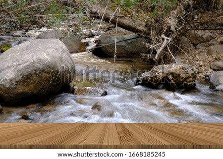 creek water stream waterfall flowing in summer forest. blur background with wood table for display product