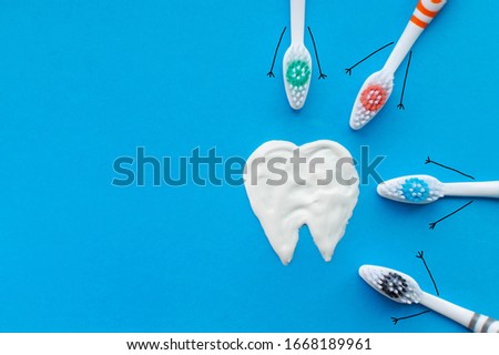 Multi-colored toothbrushes in the form of cartoon characters on a blue background with a tooth pattern drawn with toothpaste. The concept of family hygiene.