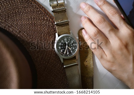Vintage military wristwatch with nato leather strap and brown straw hat. Classic timepiece mechanical watch, Men fashion and accessories. Royalty-Free Stock Photo #1668214105