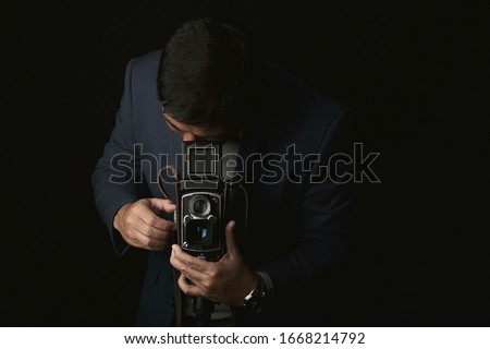 Professional photographer with vintage medium format camera, Portrait of a man in suit with twin lens classic camera in photography studio, Vintage camera collecting is trendy lifestyle.