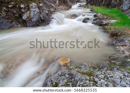 Powerful, blurred motion, colorful water of a mountain creek after rain cascading through the narrow, rocky canyon