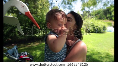
Mother caring and loving baby infant toddler outside in backyard during summer day