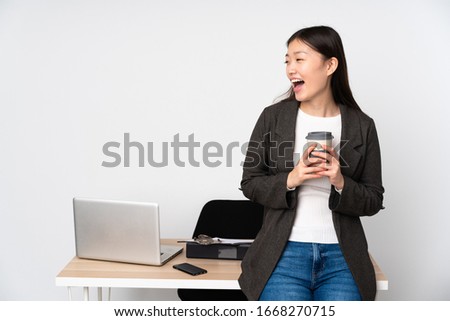 Business asian woman in her workplace isolated on white background laughing in lateral position