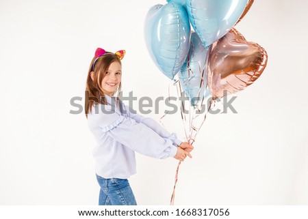 Funny girl with cats ears holding balloons in studio. Concept birthday
