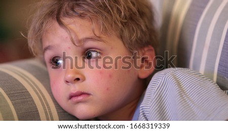 
Little boy child watching TV at night. Face of kid staring at screen in the evening