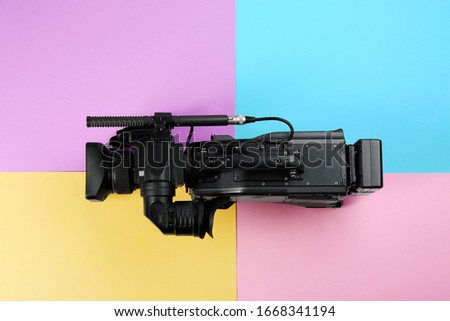 Modern video camera on color background, top view
