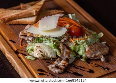 Greek salad with chicken salad, tomatoes on a wooden tray