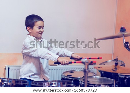 Boy drumming. boy in a white shirt plays the drums. A boy in a white shirt is drumming. toned