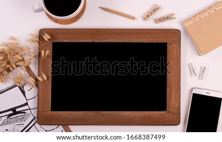 Office desk with blackboard with wooden frame and mock up. White background on a table with phone, coffee, picture, notebook and wooden accessories. Flat lay.