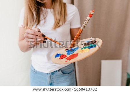 cropped shot of woman picking colors for picture on canvas in art workshop