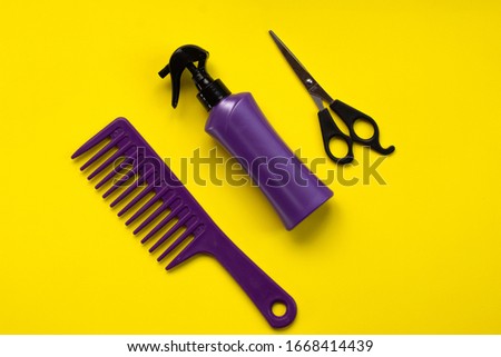 Beauty topic: stylist scissors, hairspray and stylist's comb over yellow background. Fashion and style concept.