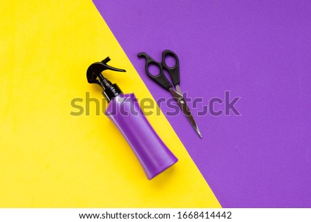 Beauty topic: stylist scissors and hairspray over purple and yellow background. Fashion and style concept.