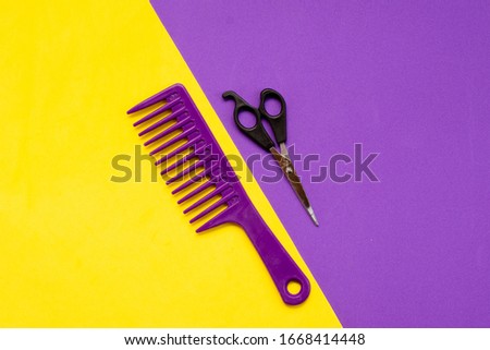Beauty topic: stylist scissors and stylist's comb over purple and yellow background. Fashion and style concept.