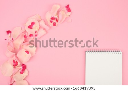 Styled flat lay mockup with floral elements on pink table. Copy space.