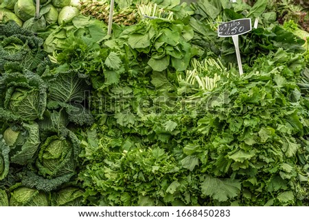 Variety of green vegetables on display with prices on a market stall at the fruit and vegetable market in Cascais Portugal