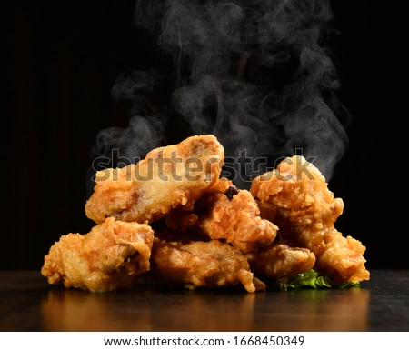 Hot and spicy bbq chicken wings with with green salad leaf and steam smoke on black background Royalty-Free Stock Photo #1668450349