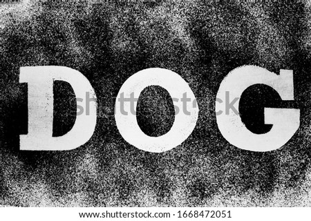 The word dog  is written in black letters on a white powder