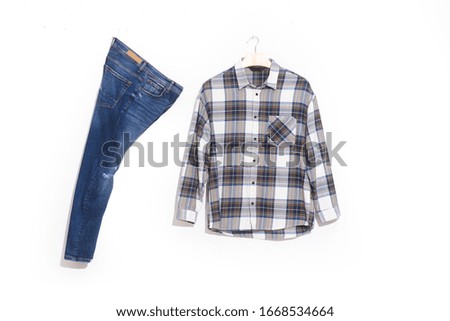 long sleeve checkered, plaid shirt on hanging and blue jeans on white background