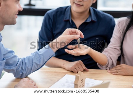 Caucasian man realtor giving house key to couple who are sign contract of rent or buy property. Real estate agent, property trade business, financial investment planning concept.