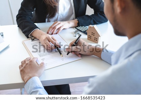Real estate brokers point to a contract paper with her pen and advise customers to sign their names. Real estate agent, property broker, real estate investment buy and sell concept.
 Royalty-Free Stock Photo #1668535423