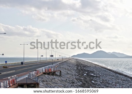 a picture of the road and the sea on a breakwater.