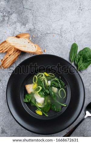 Cod ear soup with fresh spinach and cod pieces on stone background