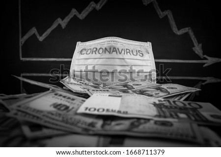 Coronavirus inscription on a medical mask on top of world international banknotes, in the background a blackboard with a stock chart with a negative trend. US dollars and Euro Coronavirus warning. Royalty-Free Stock Photo #1668711379