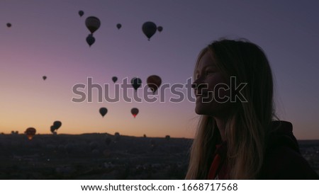 smiley female enjoy looking on beutiful air balloons at sunrise