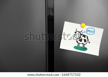 Modern refrigerator with child's drawing and magnet