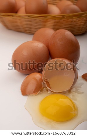 Broken chicken egg, chicken eggs in a wicker basket and eggs scattered on a white background. Close up.