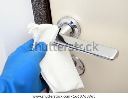 Disinfection in public places, the fight against the virus, coronavirus.Worker's hand wipes the door handles. A maid or housewife takes care of the house. Spring general or regular cleaning. 