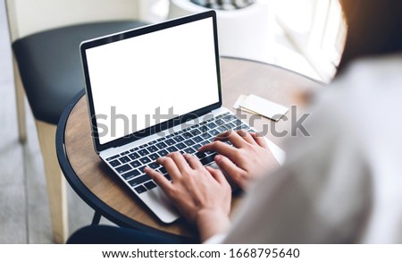 Woman relaxing using technology of laptop computer with white mockup blank screens while sitting on chair in cafe and restaurant.Communication and technology concept