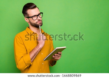 Close-up portrait of his he nice attractive pensive bearded guy in casual formal shirt student writing creating business plan isolated on bright vivid shine vibrant green color background